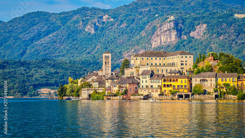 Panoramic view of San Giulio Island on Lake Orta during a golden hour and sunset, Piedmont, Italy, featuring the historic basilica and picturesque lakeside scenery surrounded by Alpine landscapes
