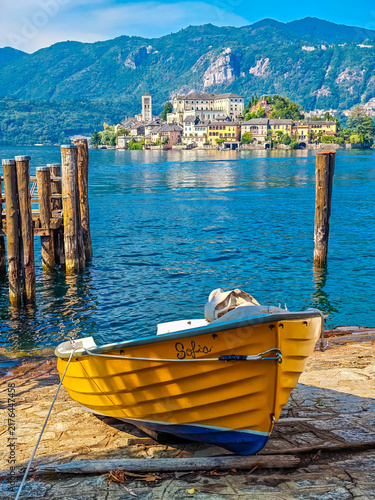 Traditional Italian atmosphere on Lake Orta, with a boat resting along the lakeshore and picturesque San Giulio Island in the background, Piedmont, Italy