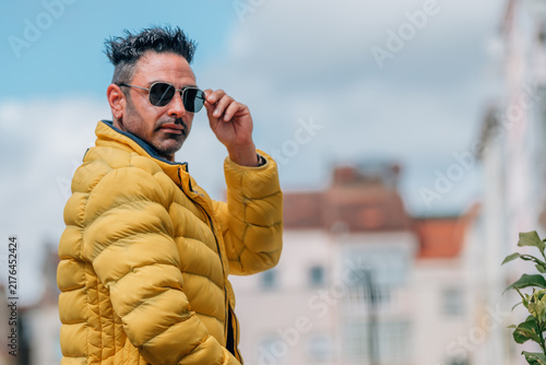 Quadro su tela Confident adult Caucasian man adjusting his sunglasses outdoors, looking over hi
