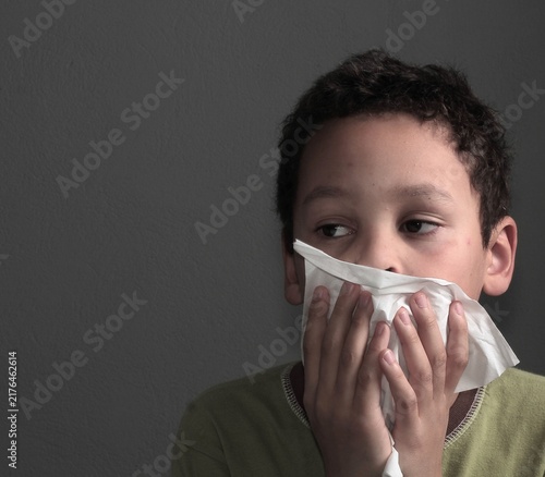 flu epidemic with child blowing nose after catching a cold with people on dark background stock image stock photo