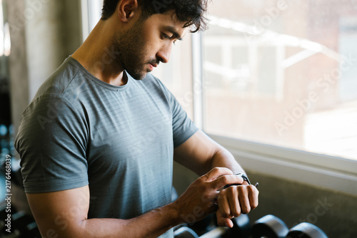 Fotografie Focused asian man exercising in gym tracking fitness health wellness progress wi