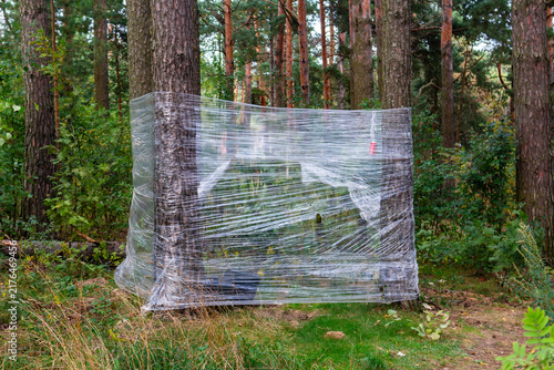 Konstfotografi Primitive makeshift forest toilet made of transparent plastic wrap stretched bet