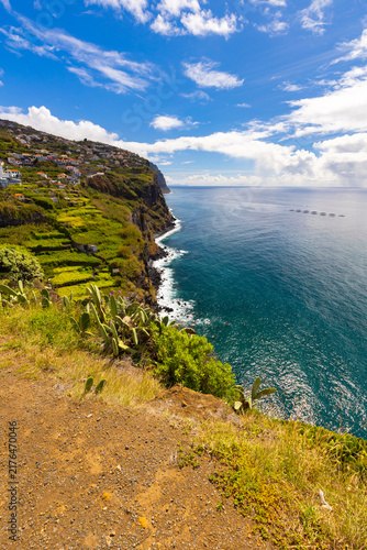 Photography Panoramic ocean view from a verdant cliffside under a blue sky with clouds in Ma