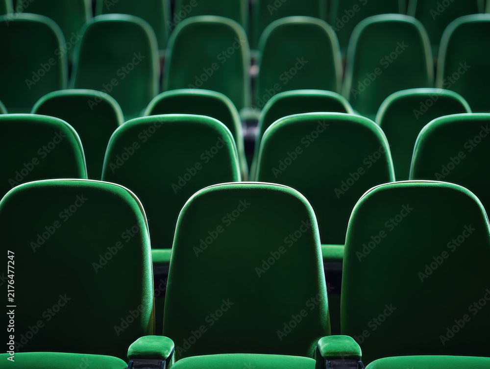 Obraz premium Rows of empty green cinema seats receding into the distance. Theatre auditorium, film screening, live performance and audience seating in entertainment venue