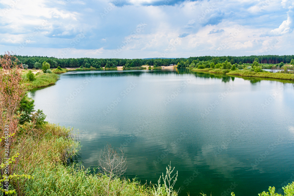 Fototapeta premium View on a lake in the abandoned sand quarry and dramatic sky