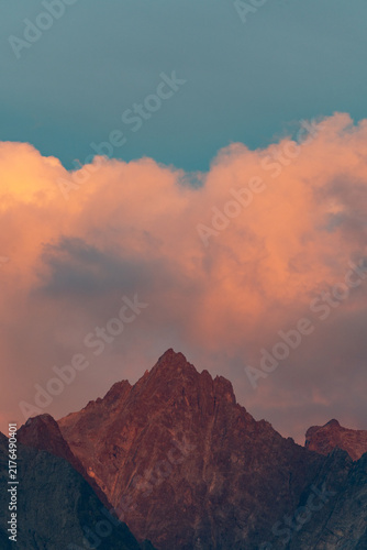 Alpenglow on Jagged Mountain Peak at Sunset With Dramatic Pink Clouds and Blue Sky