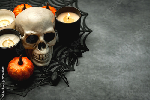 Closeup of scary evil skeleton skull with candles and Halloween pumpkins with copy space for text. Halloween concept background