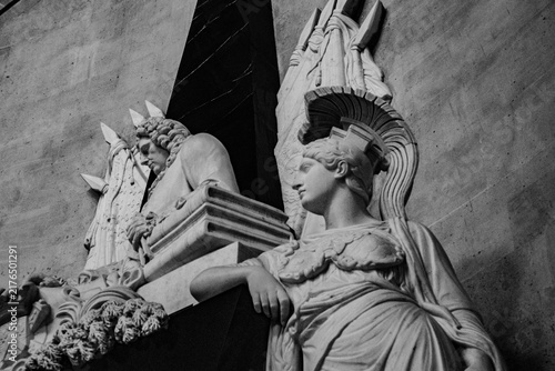Quadro su tela A Classical Marble Sculpture of a Female Warrior with a Crested Helmet Next to a