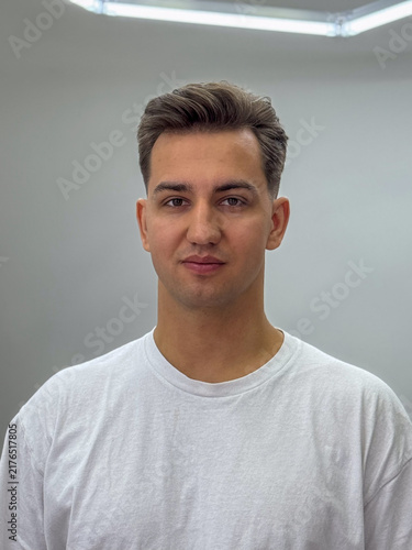 Portrait of handsome young man in white t-shirt standing against neutral background
