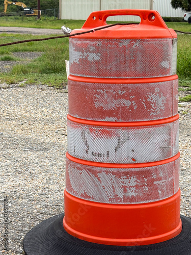 Close-up of orange construction traffic barrel with reflective stripes and copy space