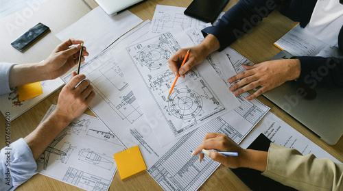 Foto Business team reviewing architectural blueprints together on a wooden table in o
