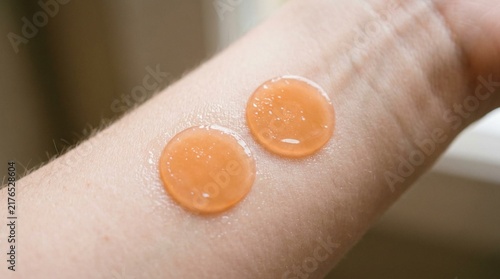 Two round orange hydrogel patches glistening with moisture on smooth pale human skin, soft natural light, closeup skincare and beauty concept