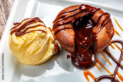 Fotografie Decadent chocolate lava cake with a gooey molten center, served with vanilla ice cream and syrup