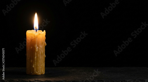 Burning candle on dark background with warm flame