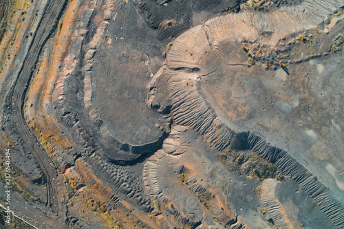 Obraz na płótnie Industrial slag heap terraces with eroded grey soil and deep tracks, aerial view