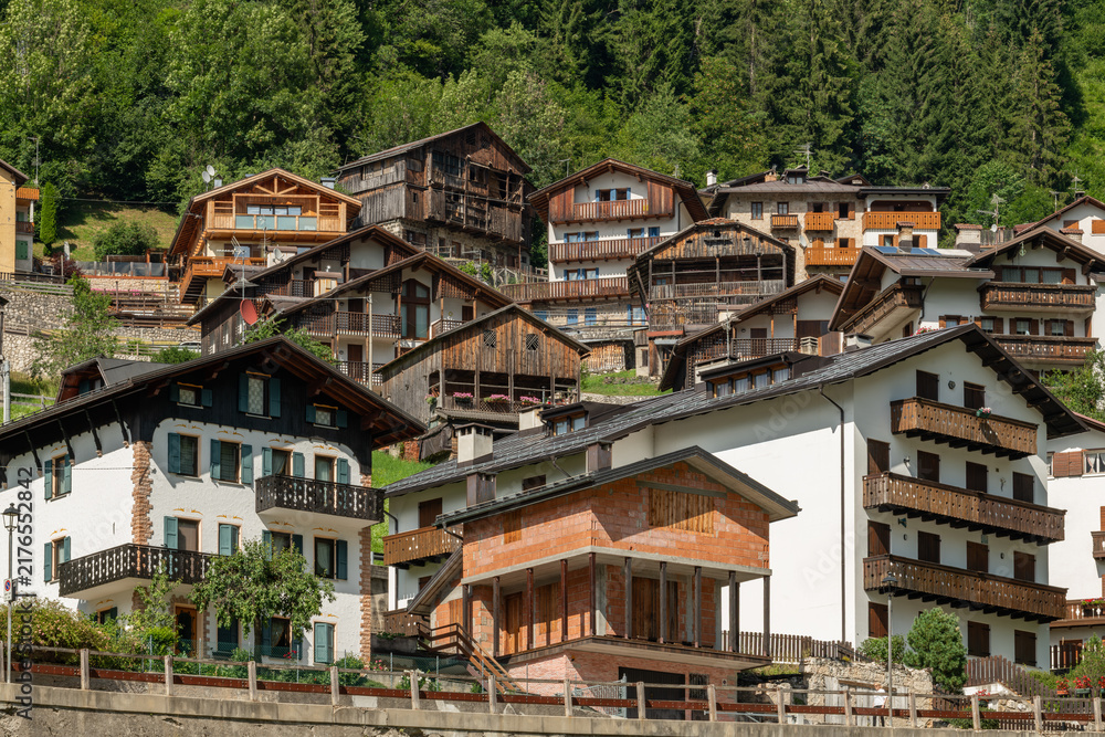Fototapeta premium Alleghe, Italy. Traditional Alpine village houses with wooden balconies on a forested mountain slope