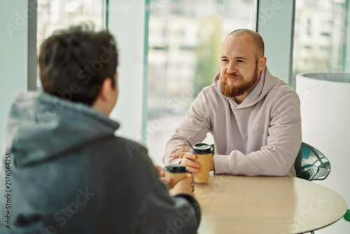 Man talking to a teenage boy seen over his shoulder