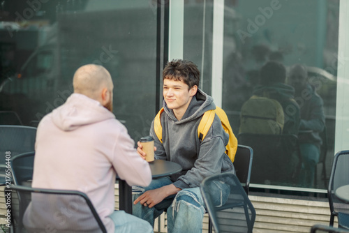 Man and teenage son in conversation at a cafe table