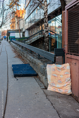 Photography Abandoned Floral Mattress and Bedding Leaning Against Metal Gate on Urban Sidewa