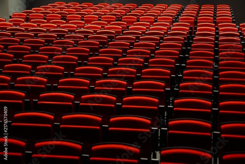 Vue rapprochée de sièges repliés de couleur rouge donnant une impression de vide et d'absence de vie. Répétition de dossiers rouges rabattus et formant des lignes noires.