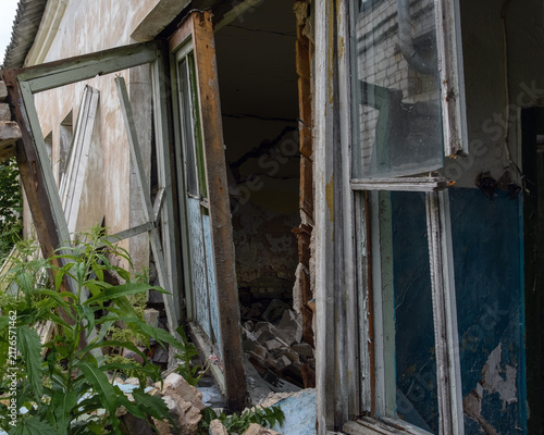 Quadro su tela Close-up of a destroyed wooden window frame and collapsed wall with debris in an abandoned house