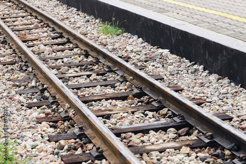 Quadro su tela Railway tracks beside station platform covered with gravel ballast and wooden sleepers