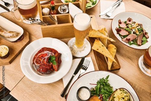 Assorted dishes and drinks served on wooden table in restaurant setting