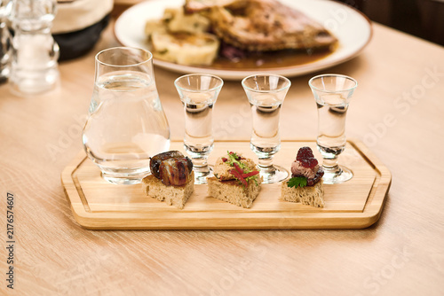 Tasting platter with shots and appetizers on wooden board in restaurant