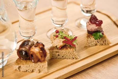 Gourmet appetizers served on wooden platter with shot glasses and drinks