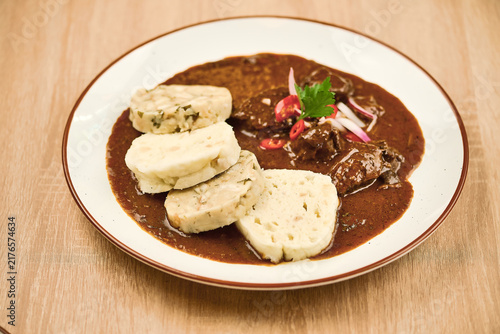 Traditional dish of meat with dumplings served on a white plate