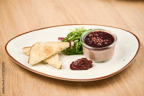 Toast with berry compote and salad on a white plate, wooden table background