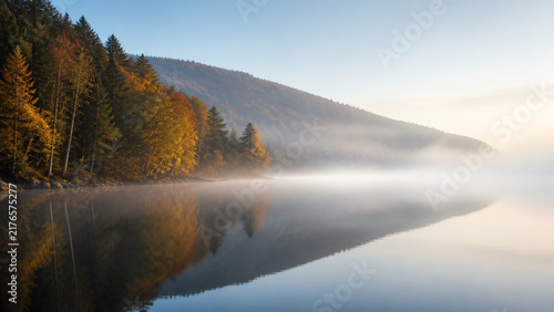 Misty autumn mountain lake at dawn with copy space
