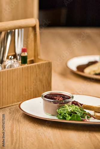 Gourmet dish with salad and sauce served on a wooden table setting