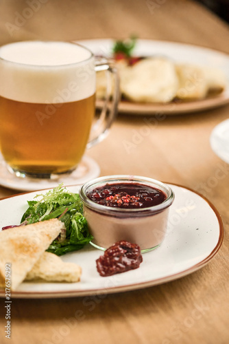Plate of dessert with jam, salad, and beer on wooden table