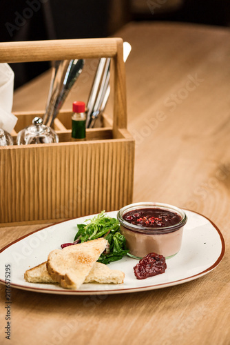 Gourmet appetizer with toast, salad, and berry compote on a plate