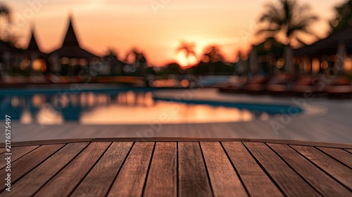 Wooden table in foreground with tropical resort pool and sunset backdrop