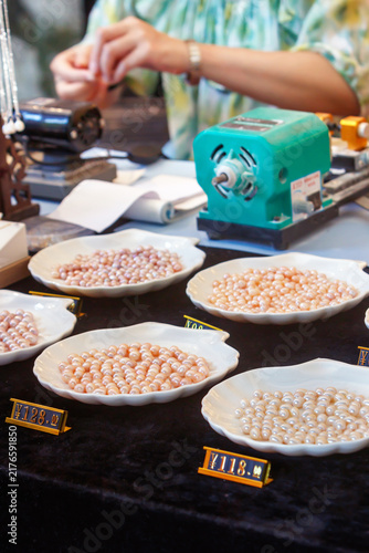 Foto Pearl vendor display with assorted pink river pearls on bowls at jewelry market