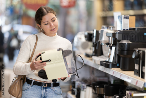 Foto Young woman carefully chooses a modern coffee machine with different modes and methods of brewing coffee