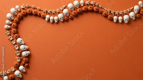 Decorative halloween garland made of small white skulls and orange beads on a solid orange background