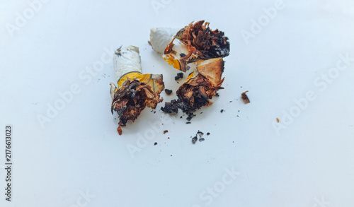 фотографія Discarded Cigarette Butt with Scattered Ashes on a Surface.