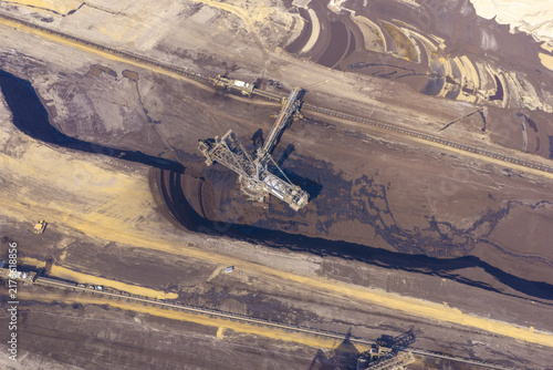 Aerial view of an open-pit brown coal mine featuring a large bucket-wheel excavator and extensive conveyor belt systems across the industrial landscape in Germany.