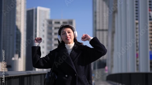 ヘッドフォンで音楽を聴きながら歩道を歩く女性