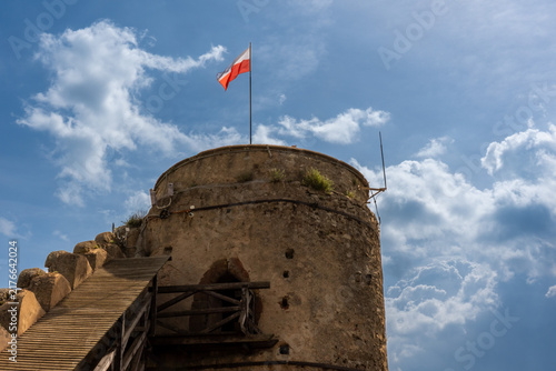 Obraz na plátně Polish flag waving above the round stone tower of medieval Chojnik Castle against dramatic blue sky and white clouds
