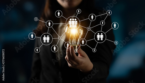 Fotografía A businesswoman holds a light bulb symbolizing innovative ideas within a network of connections, showcasing collaboration and modern technology in a professional environment