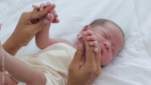 A tiny newborn baby crying on a soft bed while holding mom's fingers tightly. Emotional moment showing motherly love, comfort, family bond, and newborn health care.