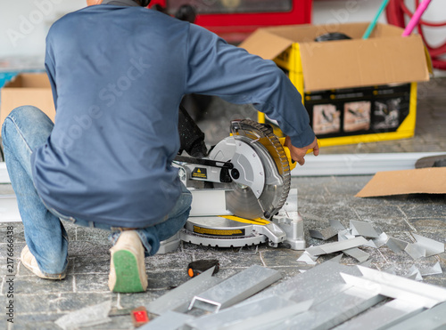 Canvas Print Construction worker using a electric circular miter saw to precisely cut aluminium profiles on a outdoor job site