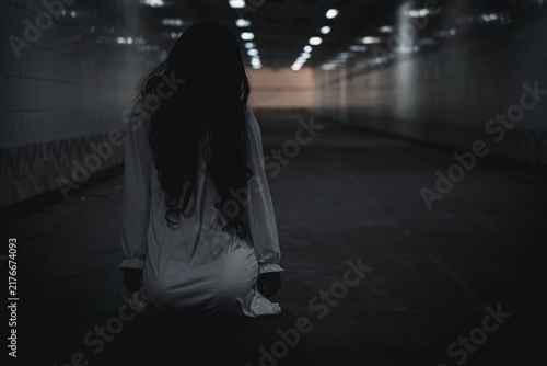 Fotografie Halloween scary woman in white dress kneeling inside dark underground tunnel, cr