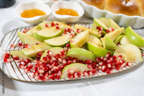 Fotografie Sliced green apples and pomegranate seeds rest on a serving platter