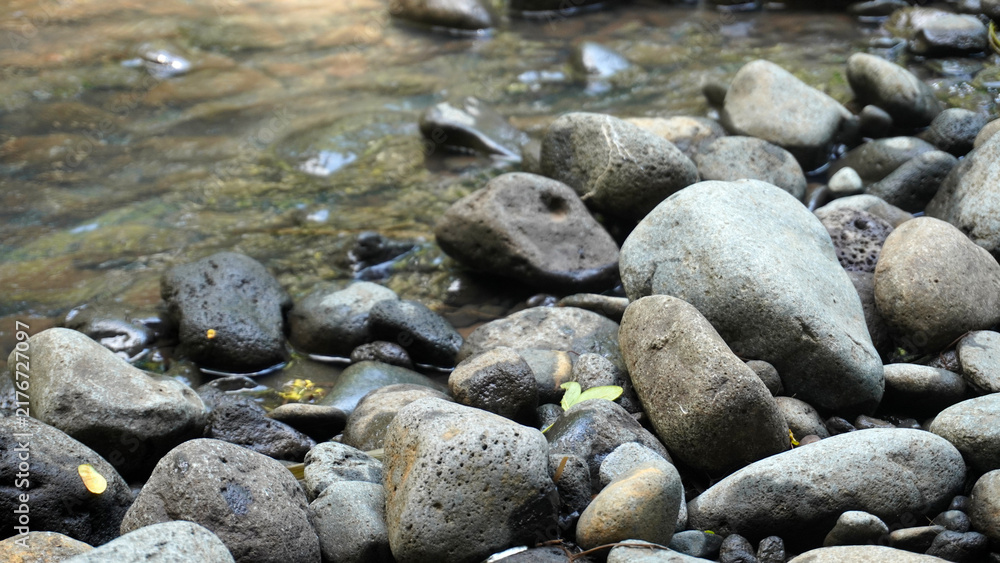 Obraz premium Stack of natural river rocks beside gentle flowing stream.