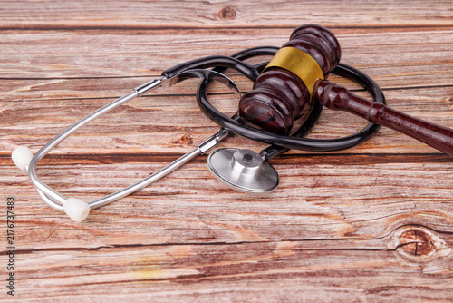 Fotografie Dark mahogany judge gavel and medical stethoscope on a wooden table